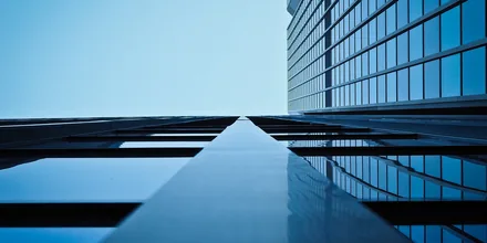 Moderne kontorbygning i glas spejlet mod en blå himmel